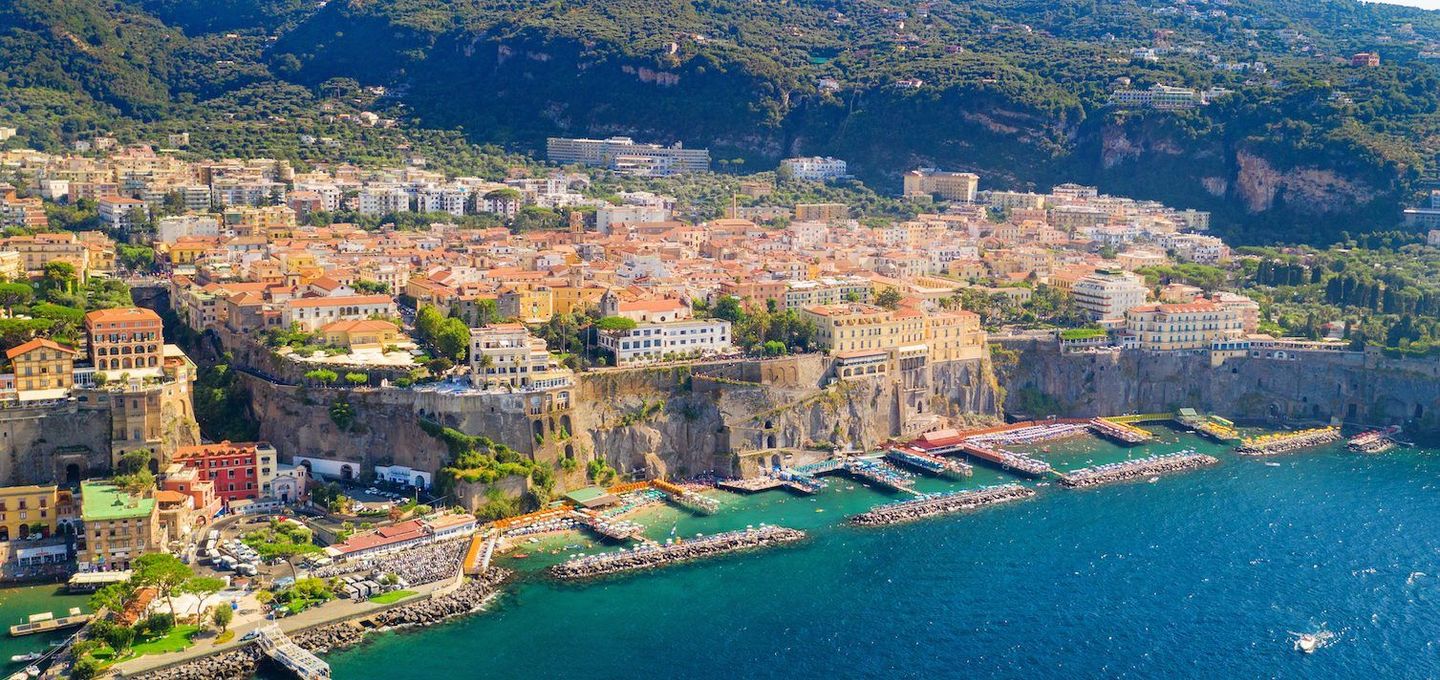 Sorrento's cliffside landscape with colorful buildings, clear blue sea, and beach ideal for tour experiences.