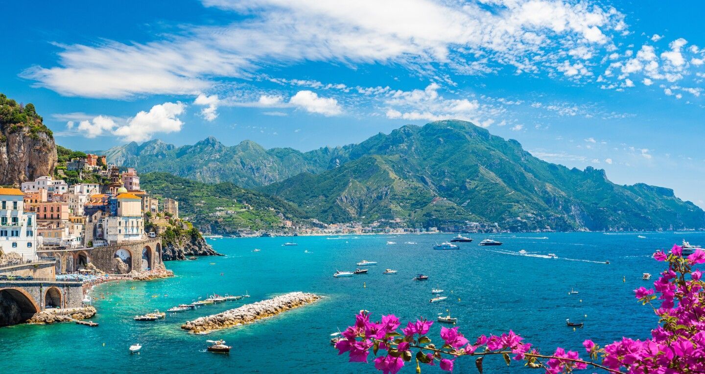 Stunning Amalfi Coast view, with pink bougainvillea, azure waters, and cliffside villas.