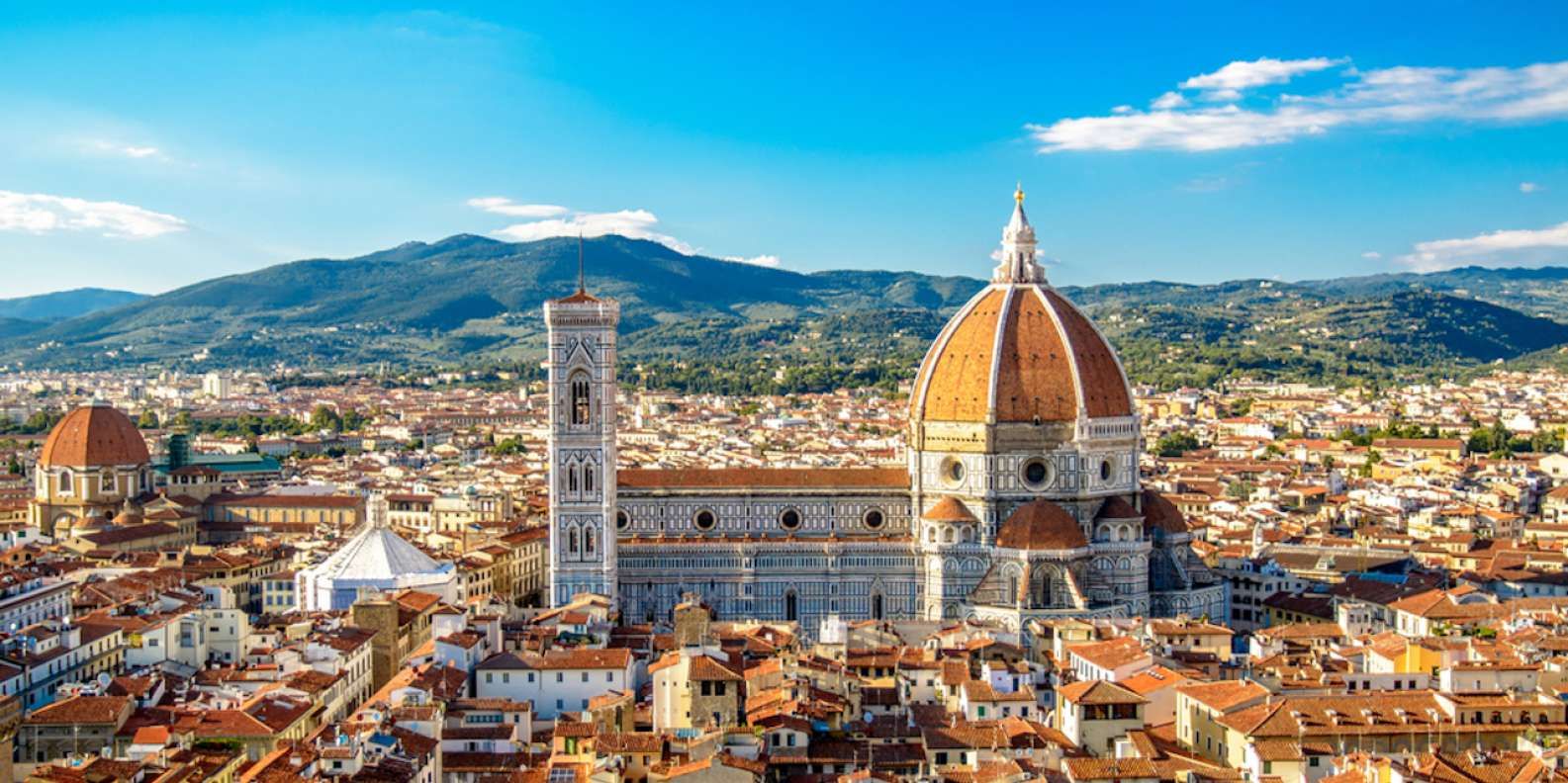 Florence skyline with the Duomo's red dome and Giotto's Campanile, amidst city and Tuscan hills.