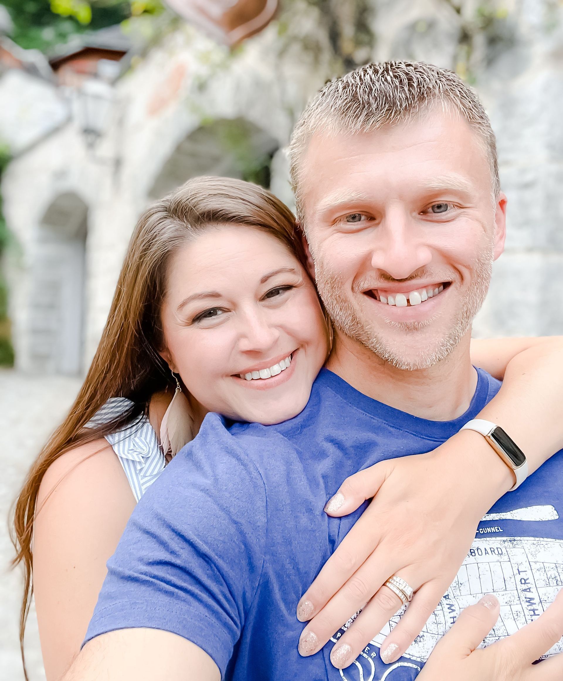 Woman hugging a smiling man outdoors. They are fair-skinned with brown and blonde hair, respectively.