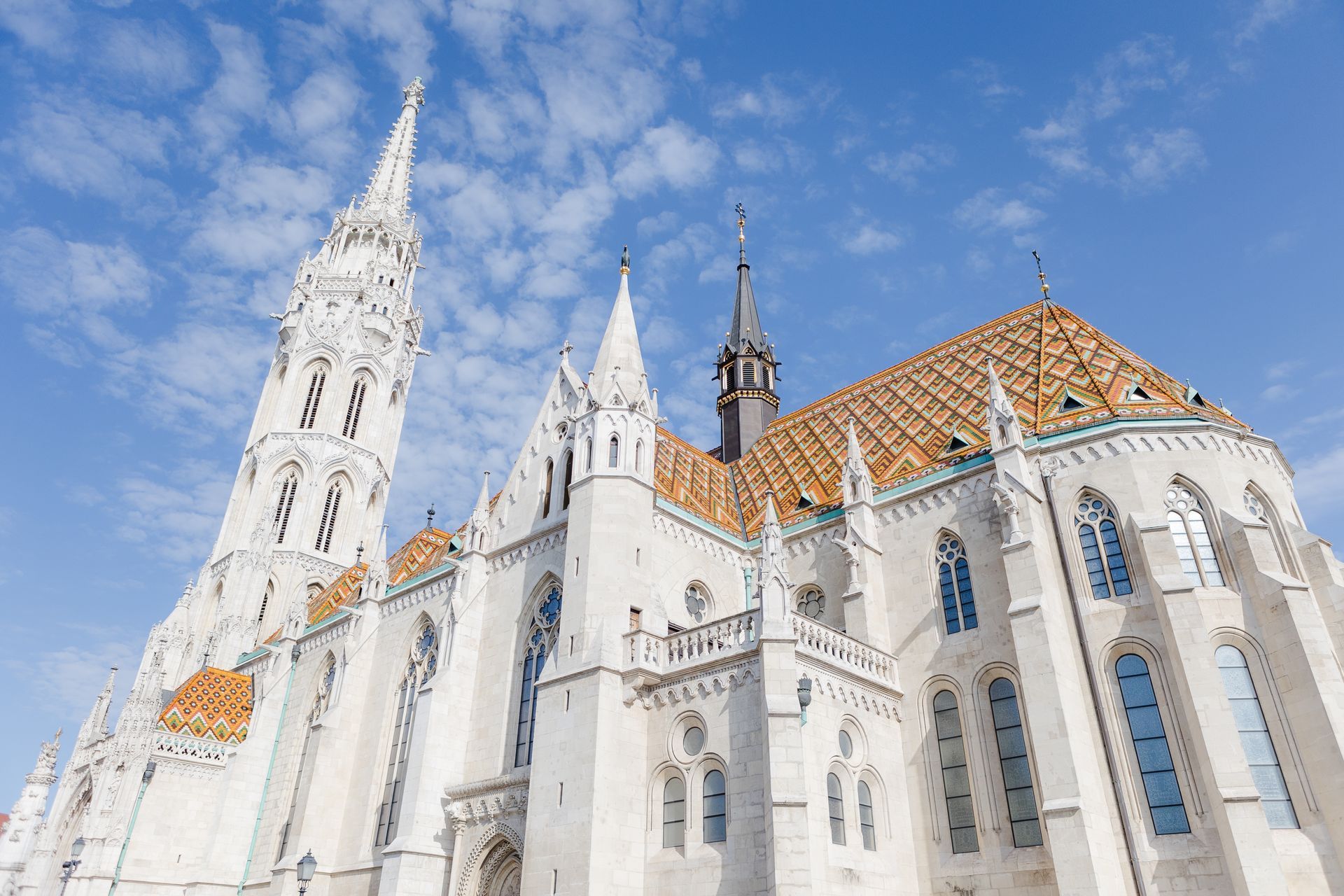 Whitewashed Matthias Church with colorful tiled roof against a blue sky. Budapest, Hungary.