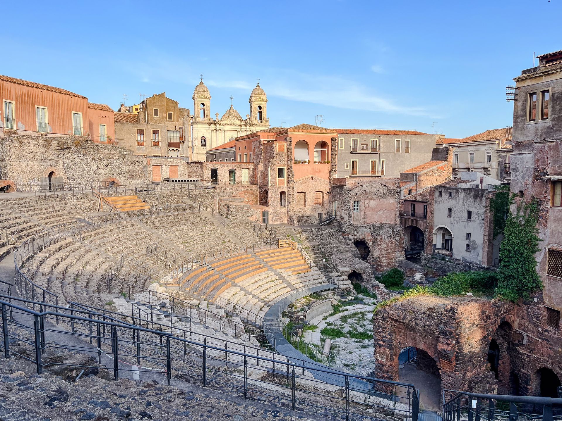 Ruins of an ancient Roman theater in Catania, Sicily. Stone structures, blue sky.