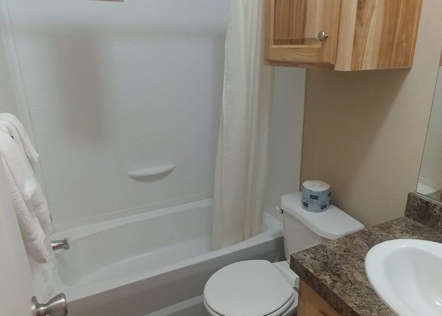 A small, clean bathroom with a white bathtub, toilet, and sink.