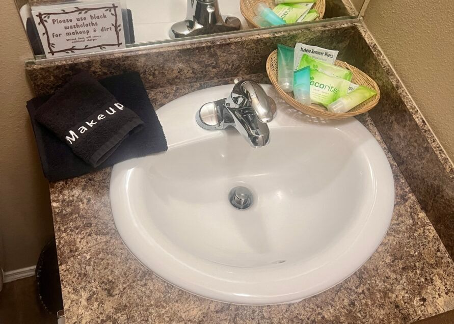 Bathroom sink with a black makeup towel and toiletries basket on the counter.