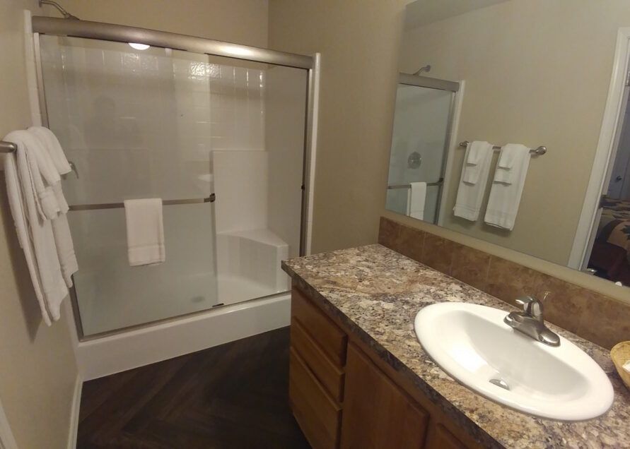 Bathroom with a shower, vanity, and towels. The shower has a sliding glass door.