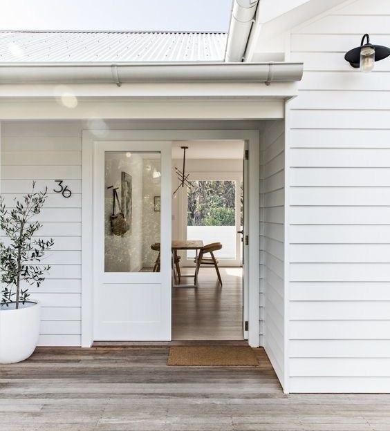 A white house with white cladding and glass door