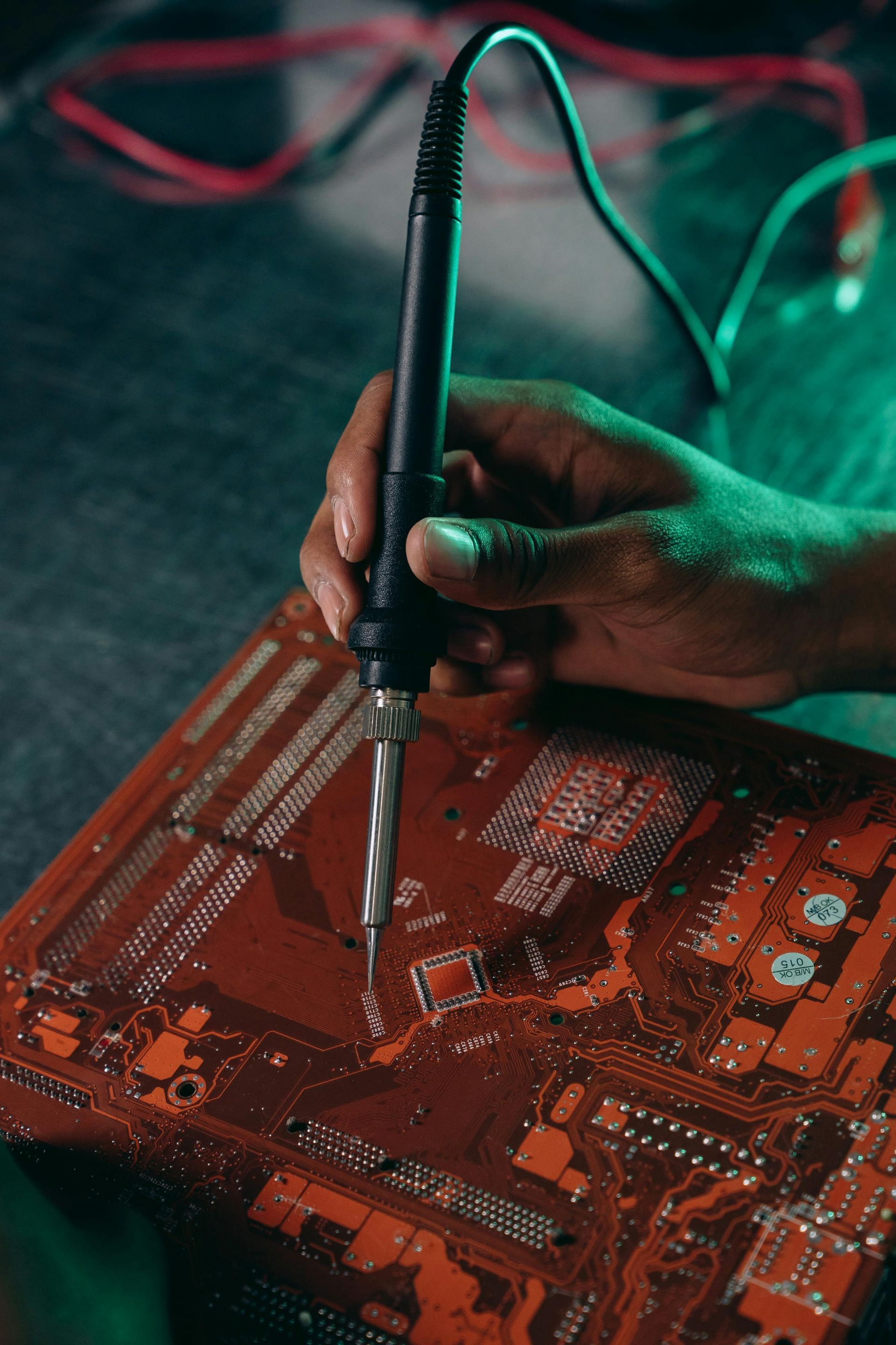 A person is soldering a motherboard with a soldering iron.