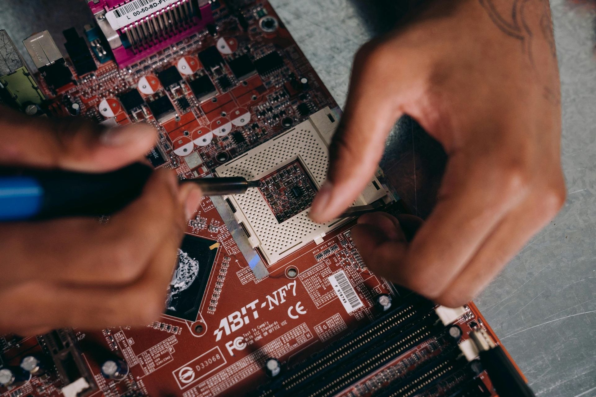 A person is working on a motherboard with a soldering iron.