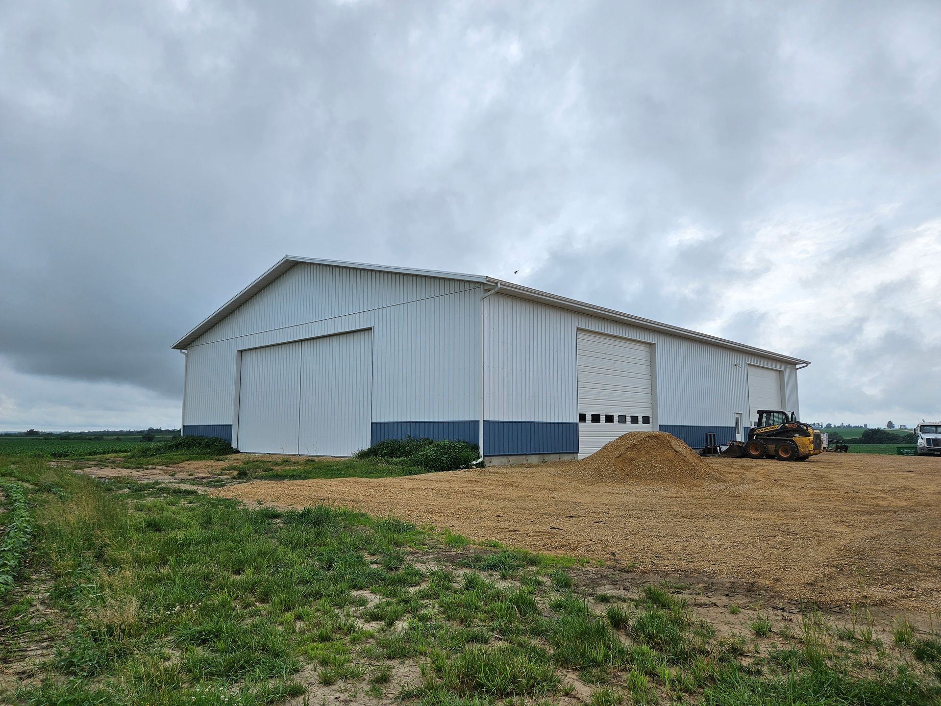 A large white building is sitting in the middle of a field.
