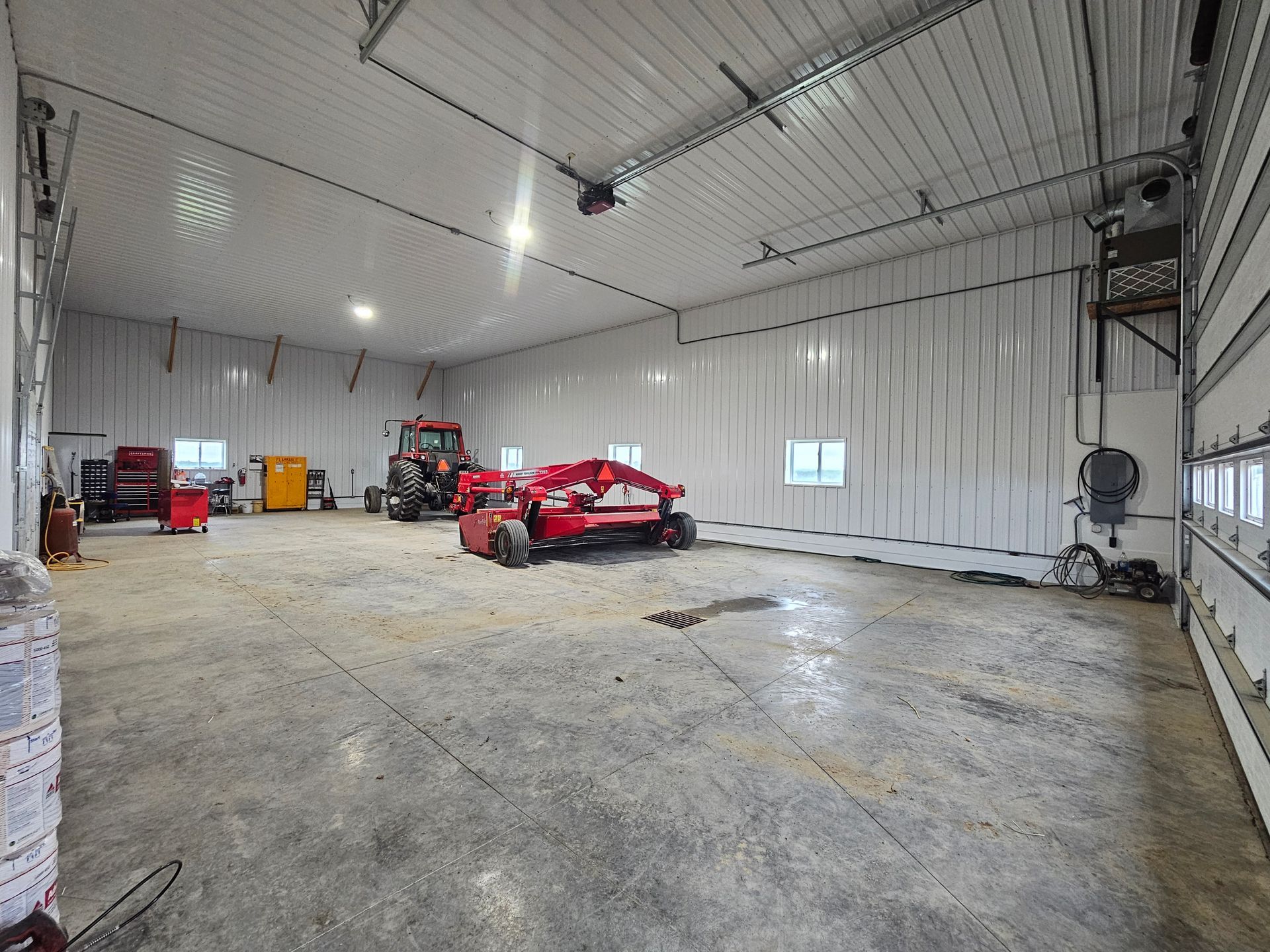 A large garage with a red tractor parked inside of it.