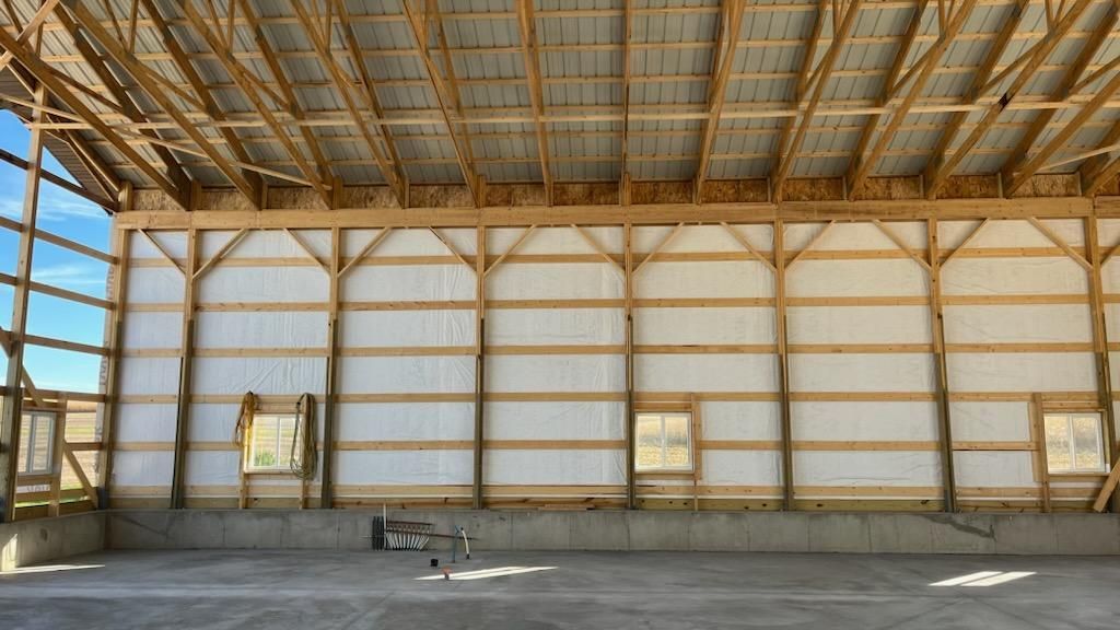 The inside of a building with wooden beams and a concrete floor.