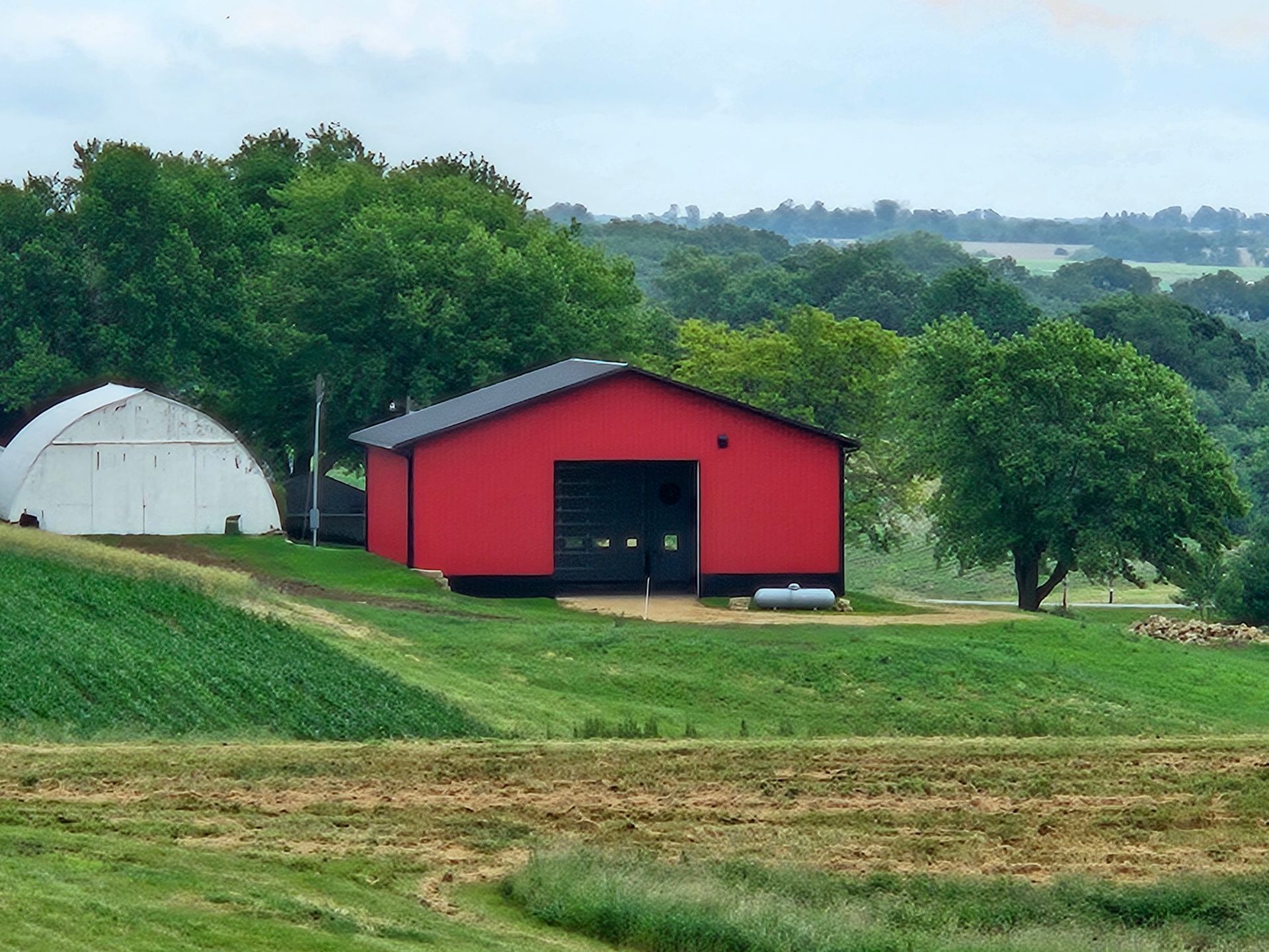 A red barn sits in the middle of a grassy field