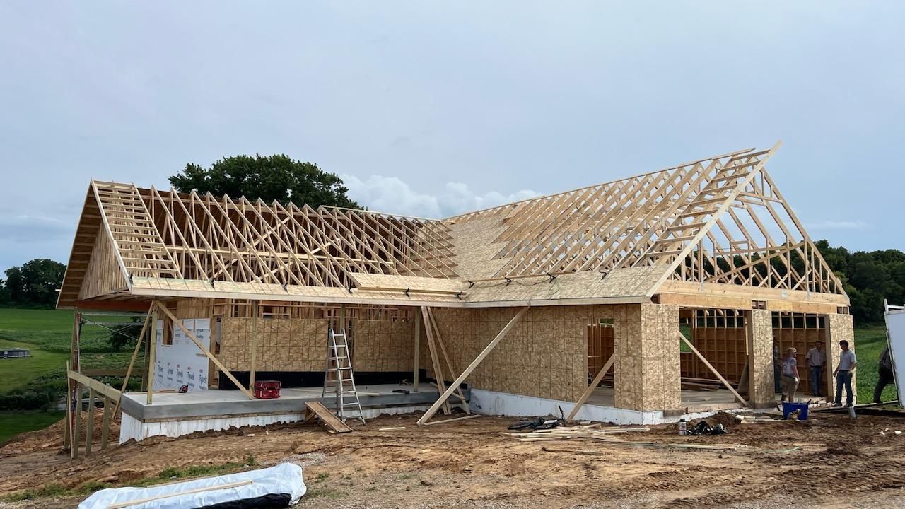 A large wooden house is being built in a field.