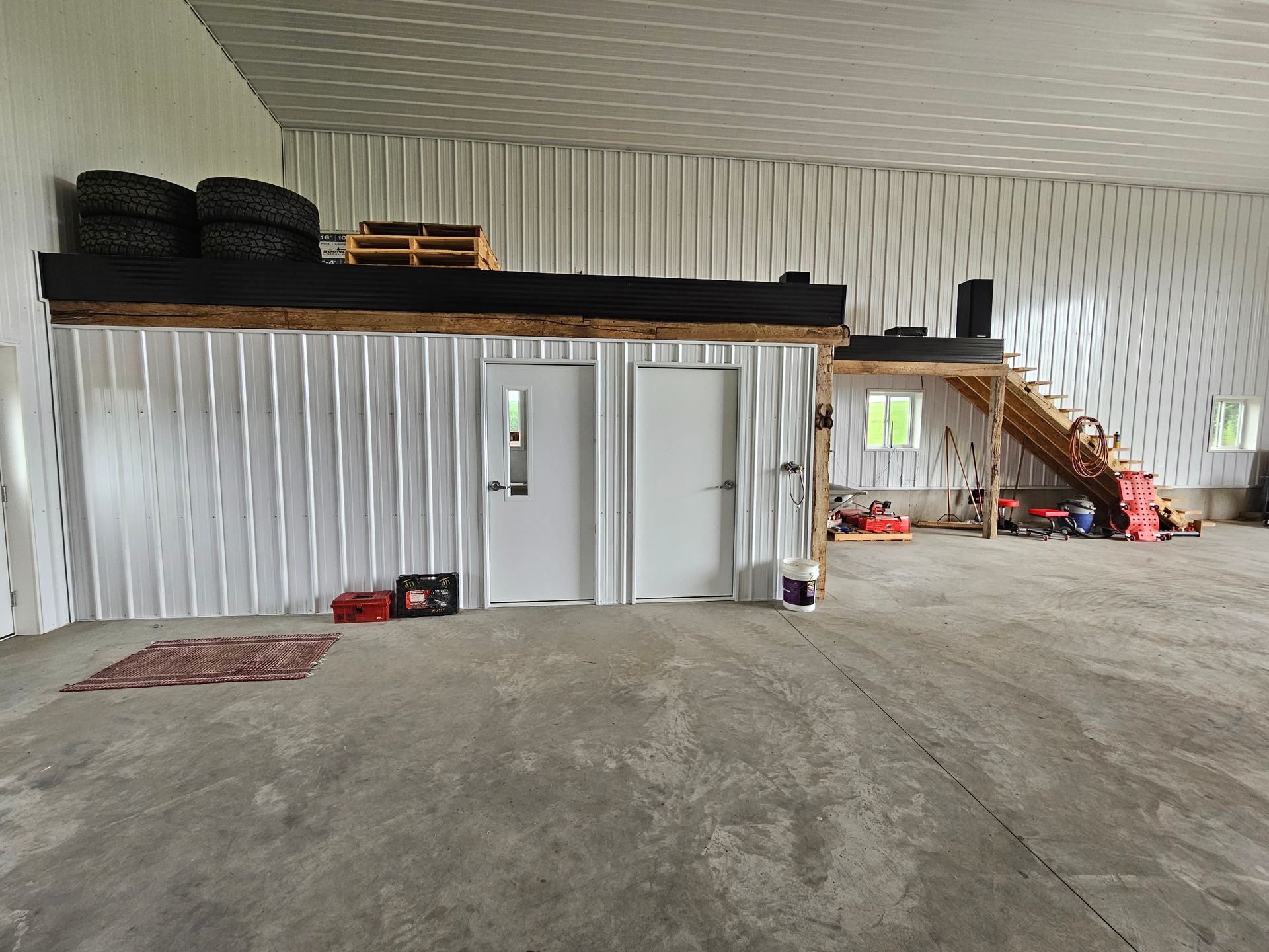 A large empty room with a loft and stairs