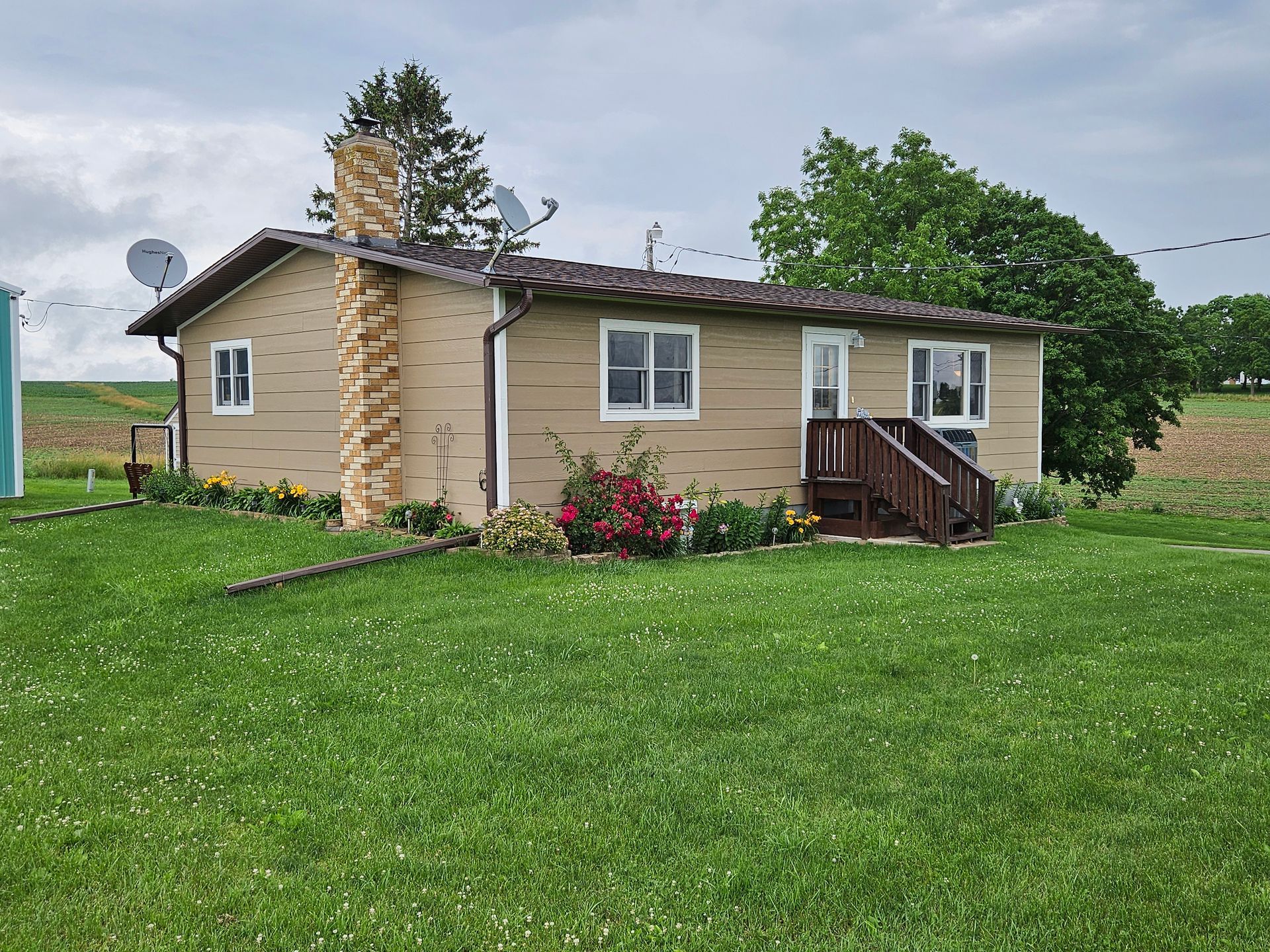 A small house is sitting in the middle of a lush green field.