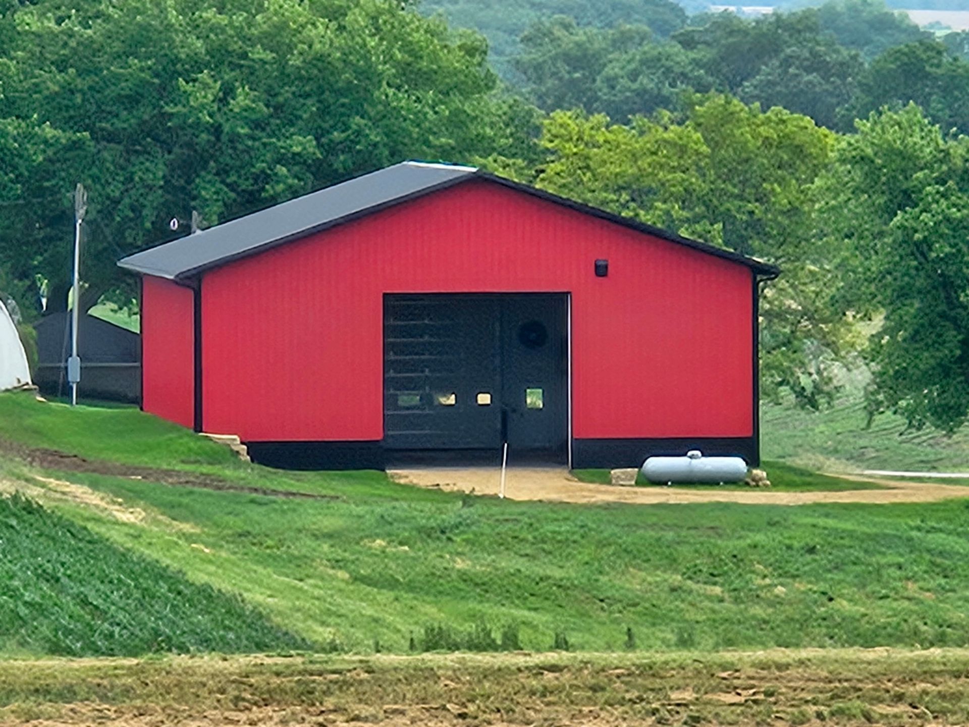 A red barn sits in the middle of a grassy field