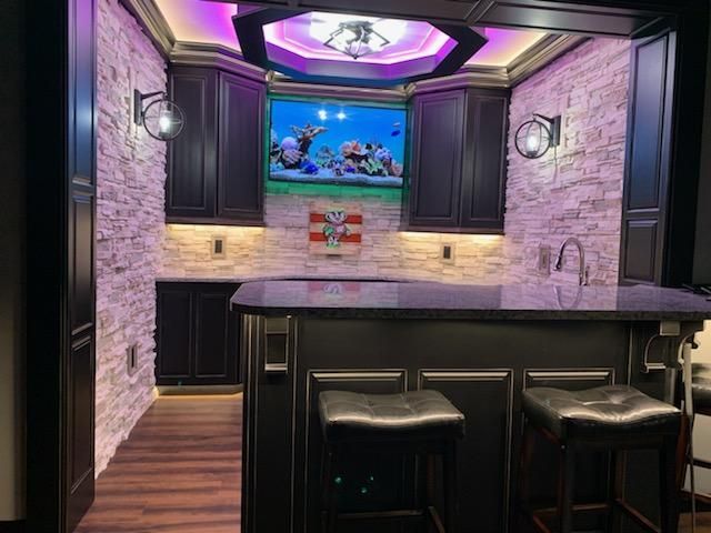 A kitchen with a bar and a television on the wall.