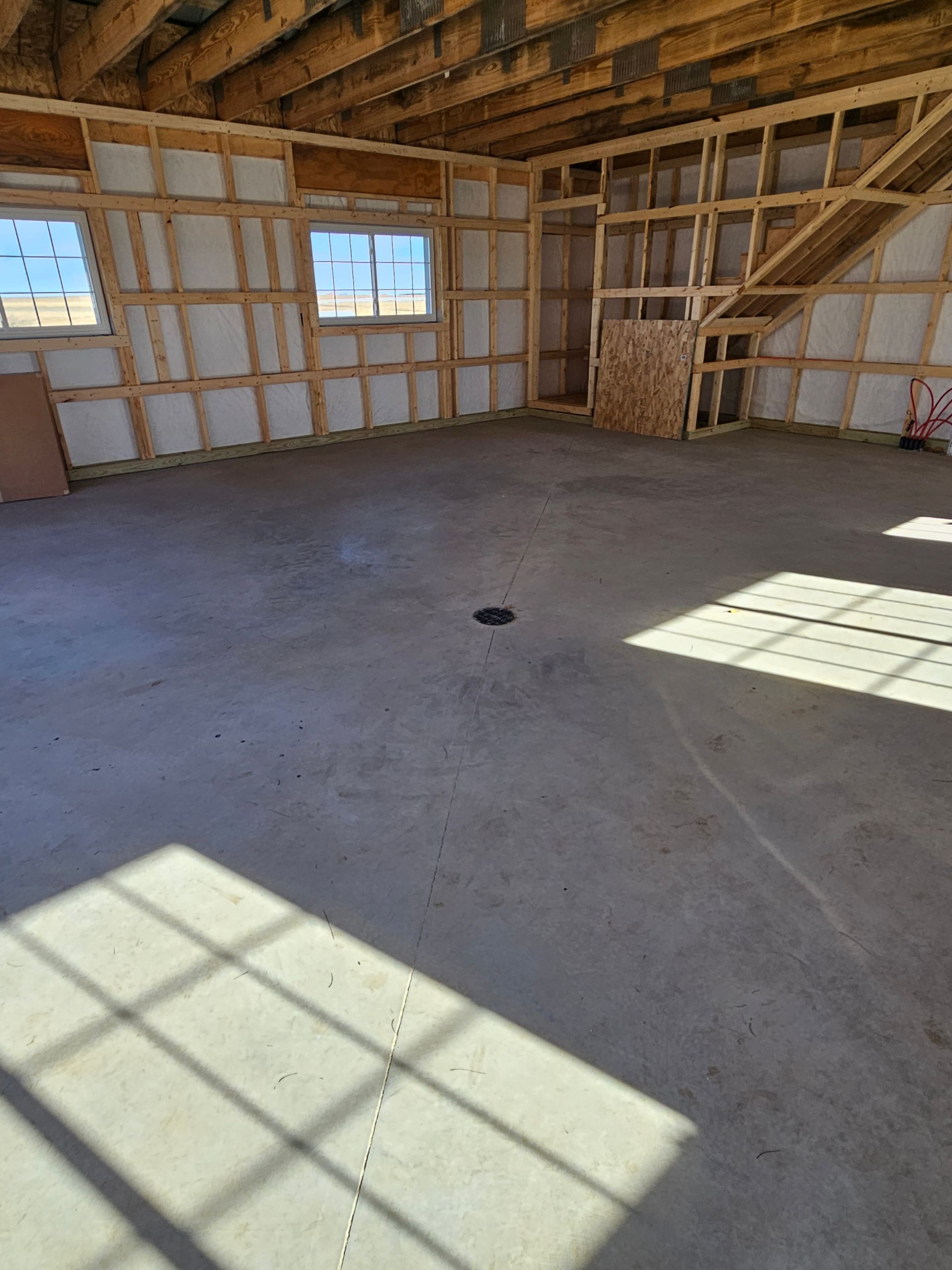 A large empty room with a concrete floor and wooden walls.