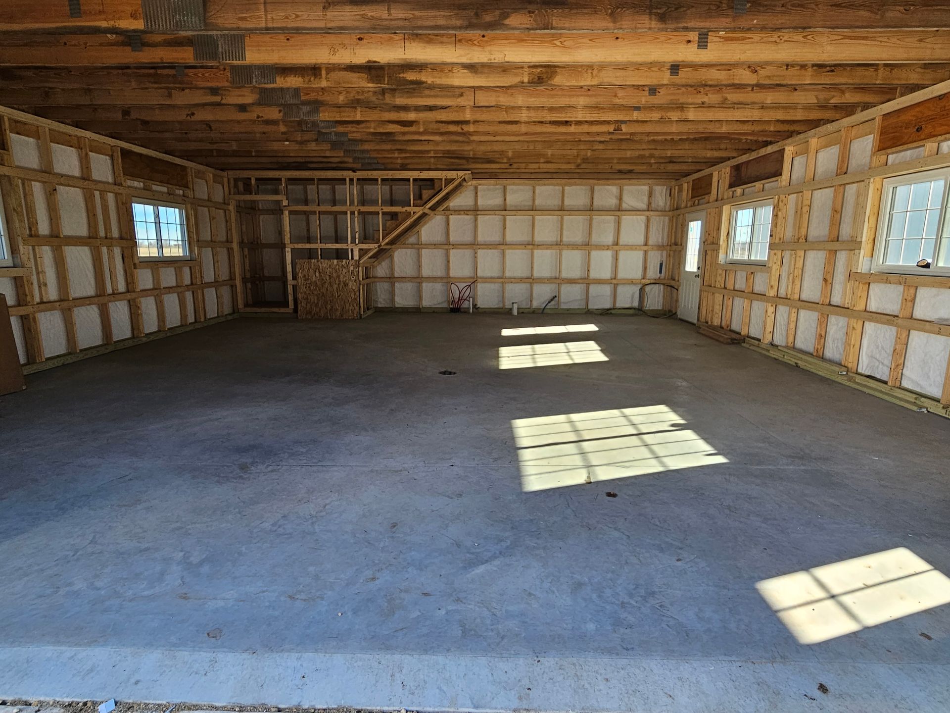 An empty garage with wooden beams and a concrete floor