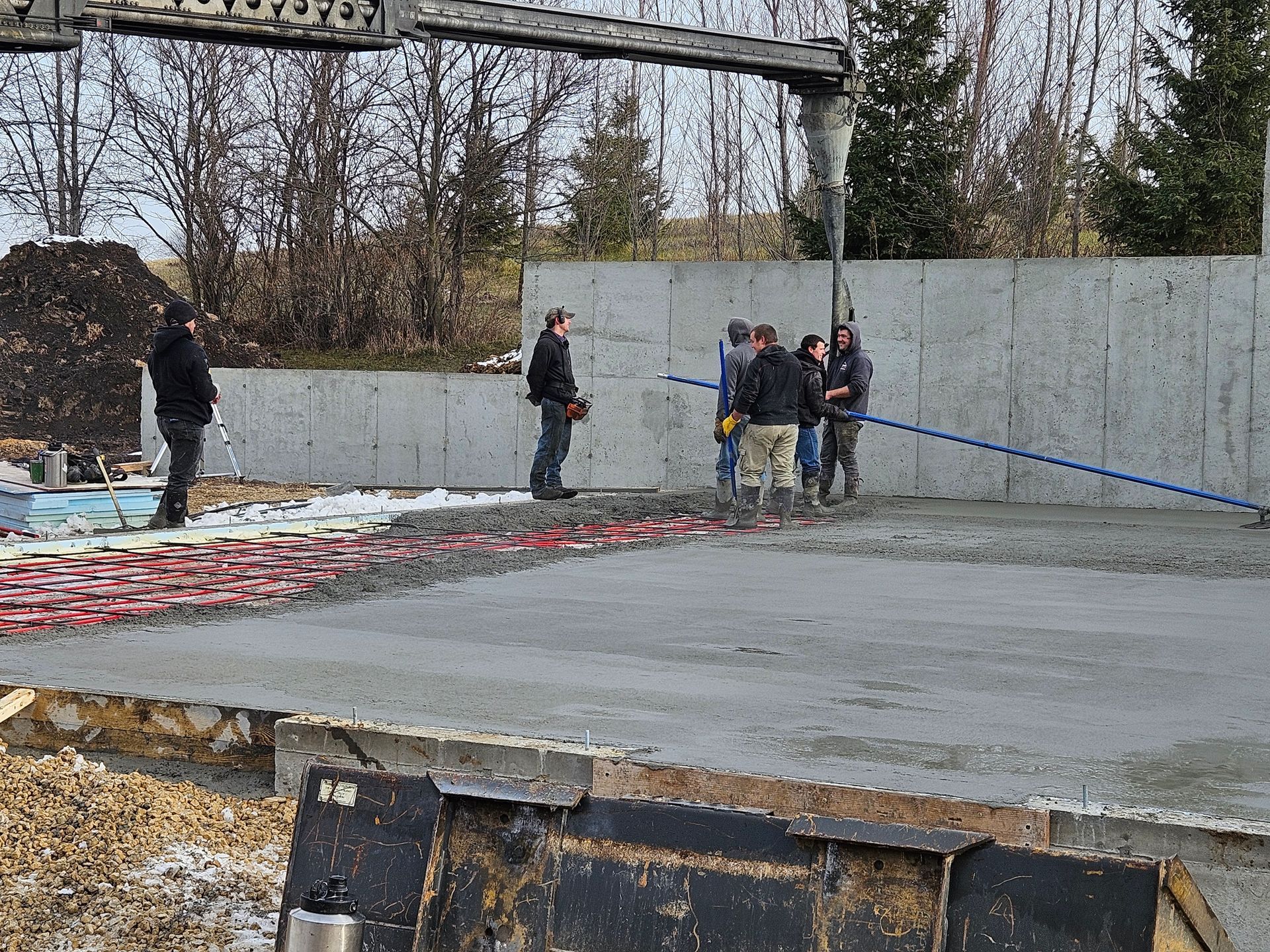 A group of construction workers are standing on a concrete floor