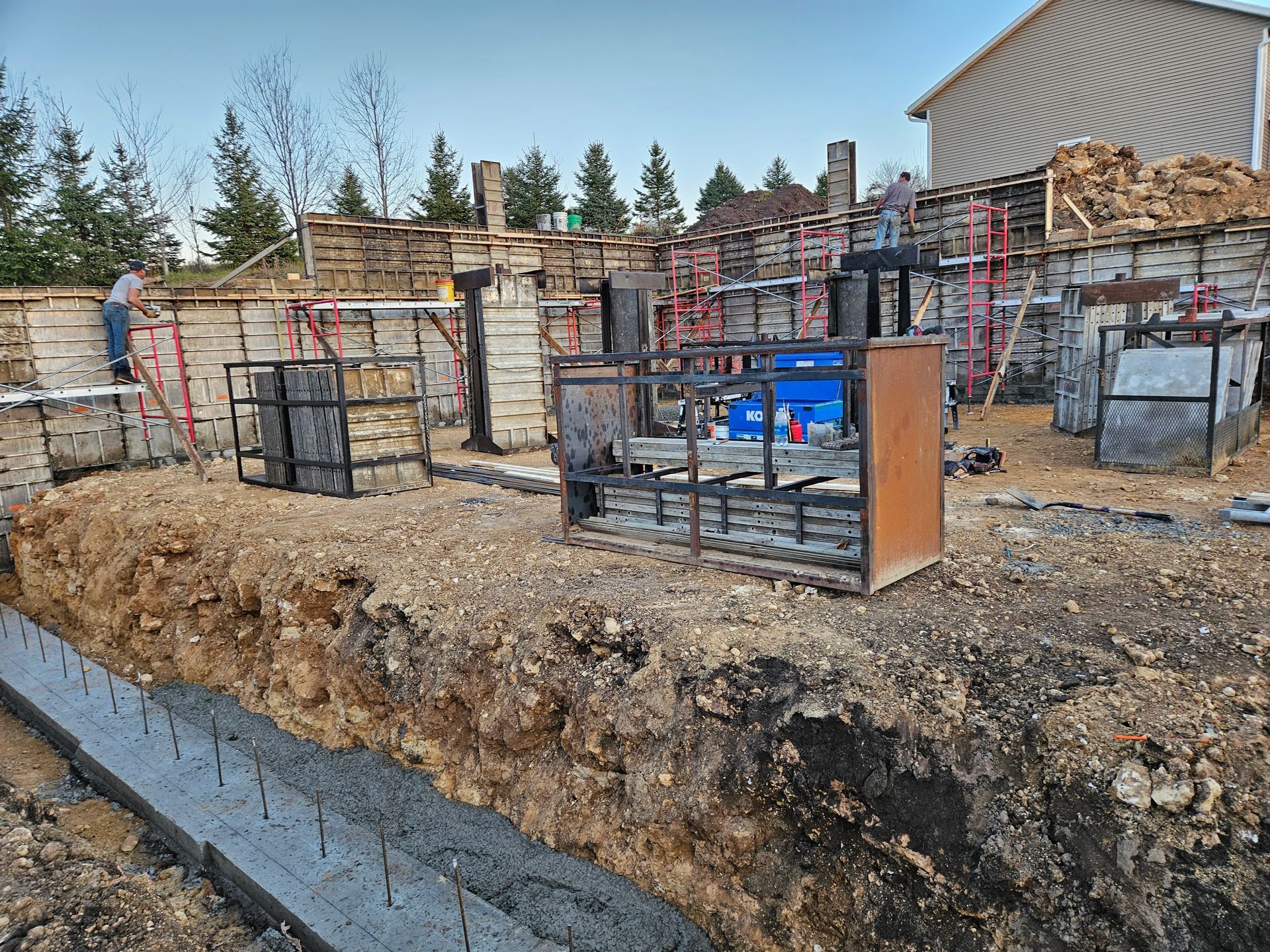 A man is standing in the dirt next to a building under construction.