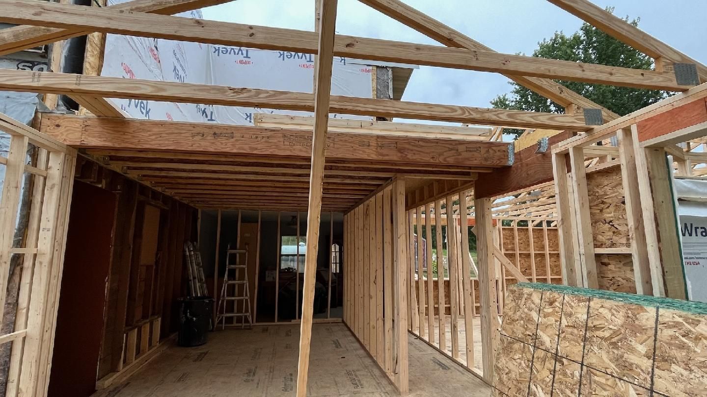 A house is being built with wooden beams and a roof.