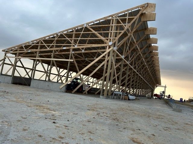 A large wooden structure is being built on top of a dirt hill