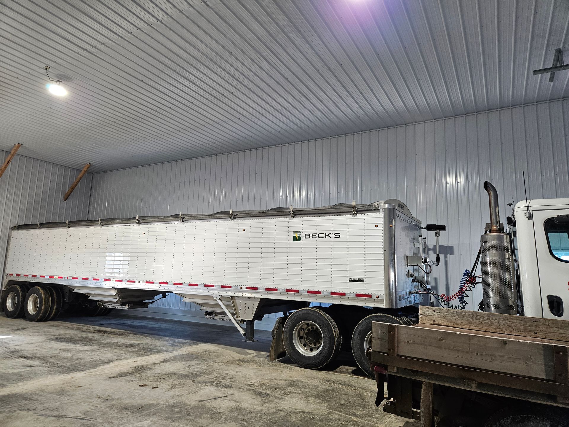 A semi truck is parked in a warehouse next to a truck.