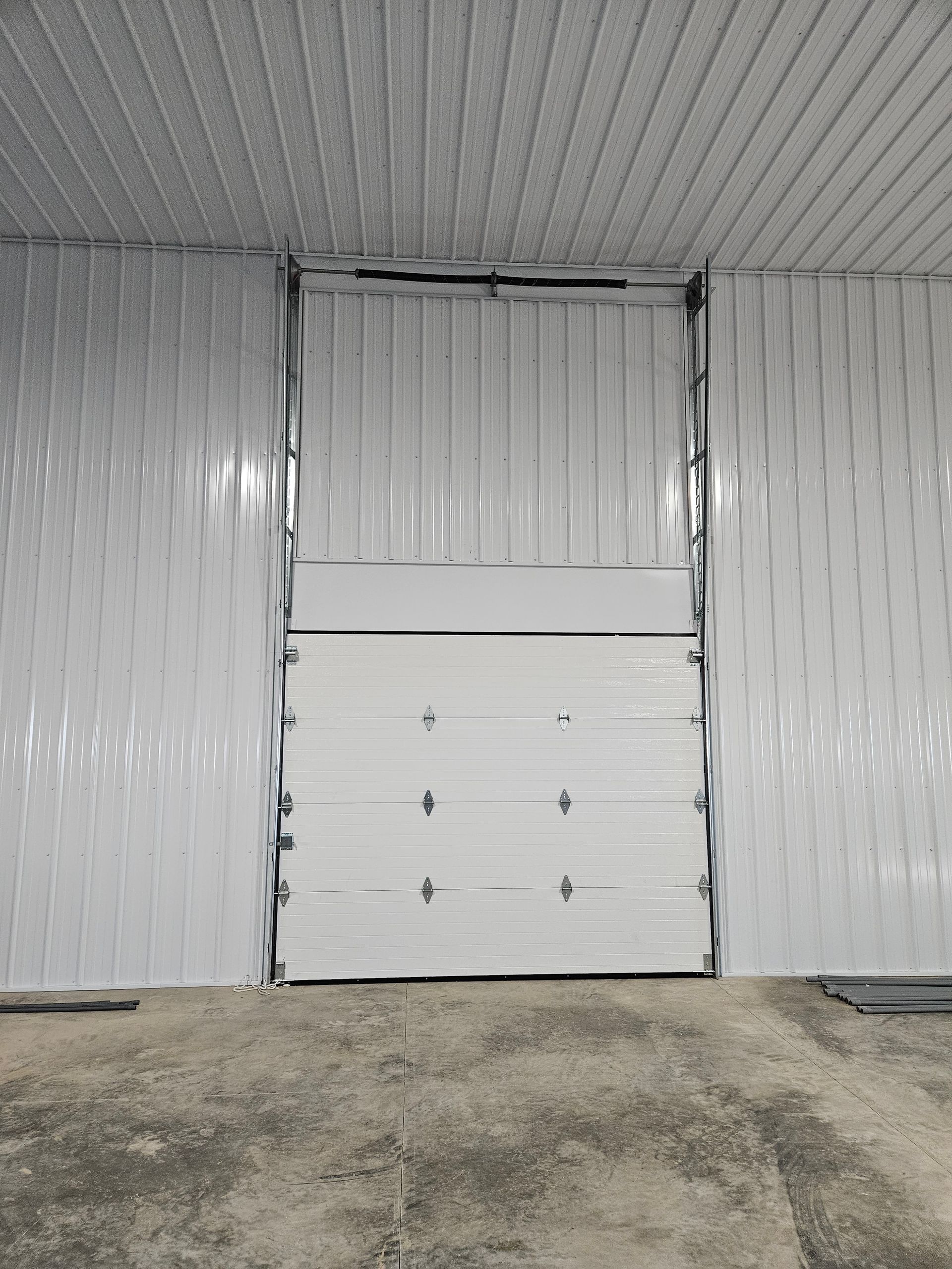 A white garage door is open in an empty garage.