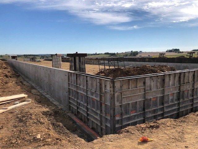 A large concrete wall is being built in a dirt field.