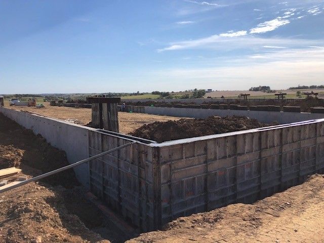 A large concrete wall is being built in a dirt field.