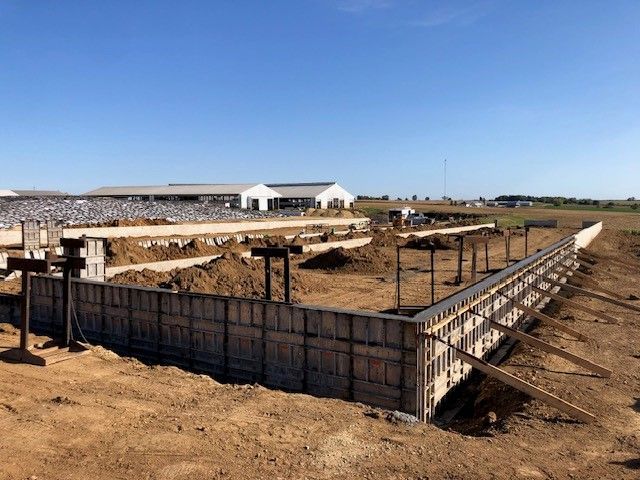 A large concrete wall is being built in a dirt field.