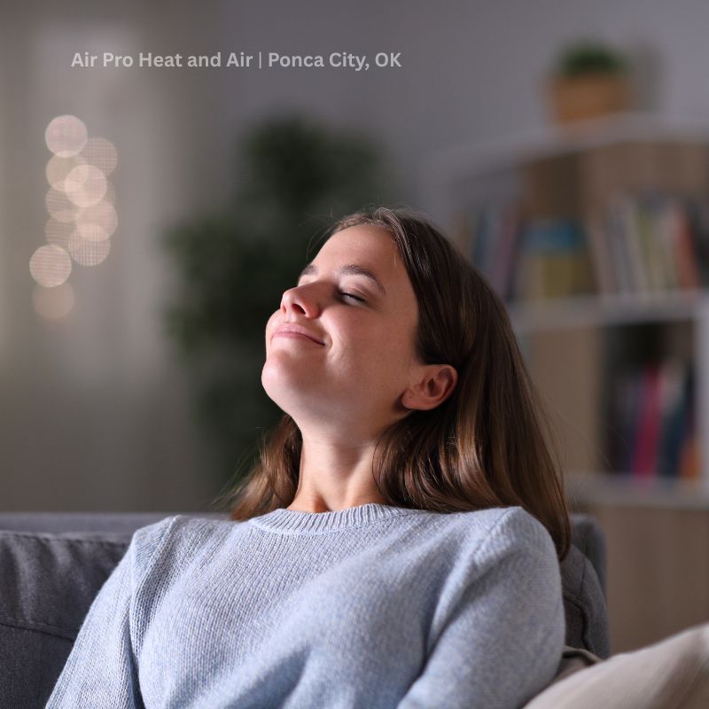 A woman is sitting on a couch happy with her eyes closed