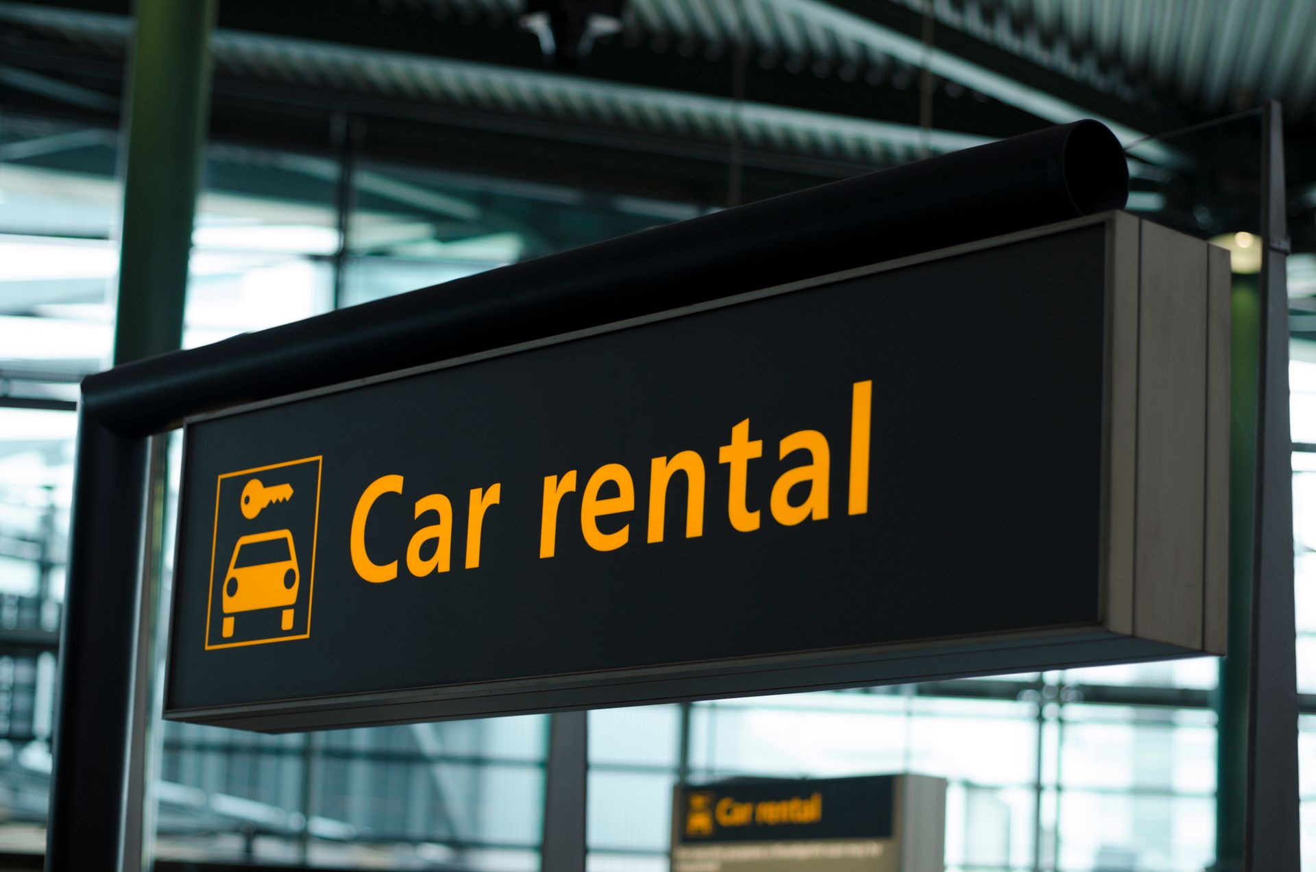 Sign for Car rental with a car icon and text in orange.