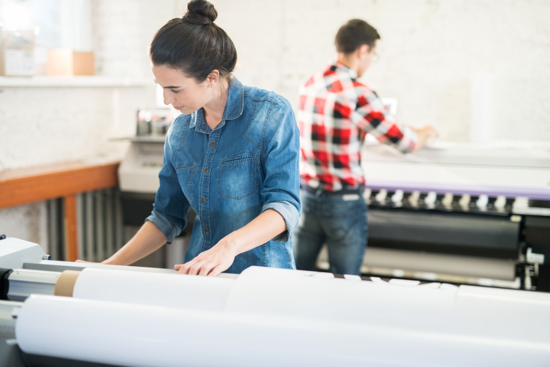 A woman is working on a large roll of paper in a factory.
