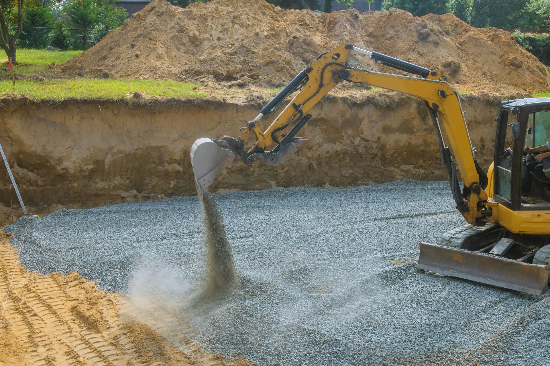 A yellow excavator is digging a hole in the ground.