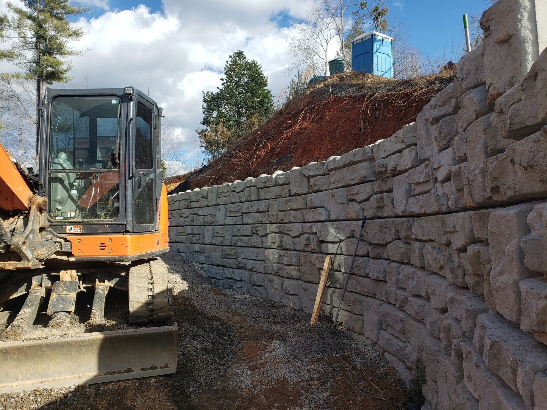 A bulldozer is working on a stone wall.