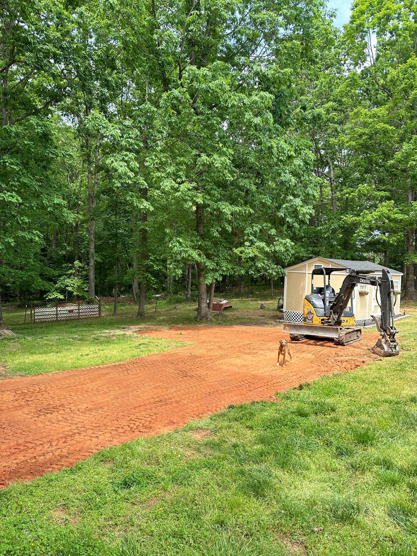 A bulldozer is driving down a dirt road in a grassy field.