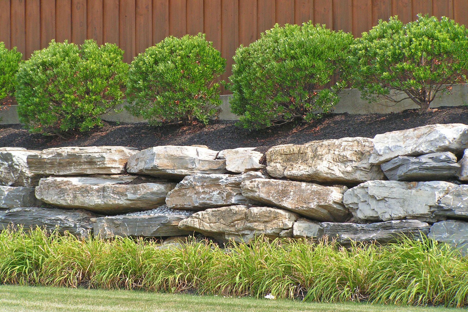 A large rock wall with a fence in the background