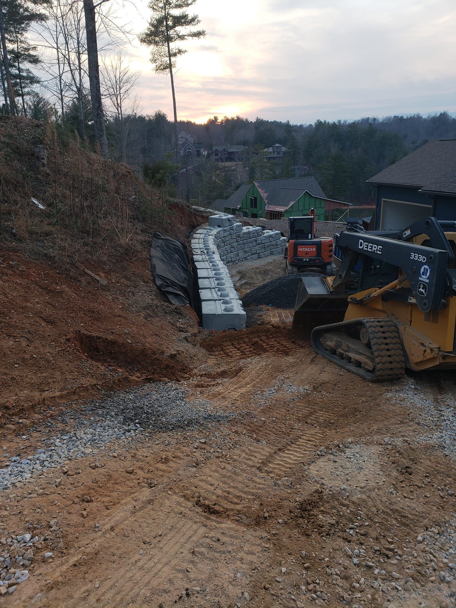 A bulldozer is driving down a dirt road next to a house.