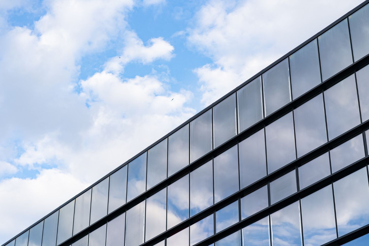 A large building with a lot of windows against a blue sky with clouds.