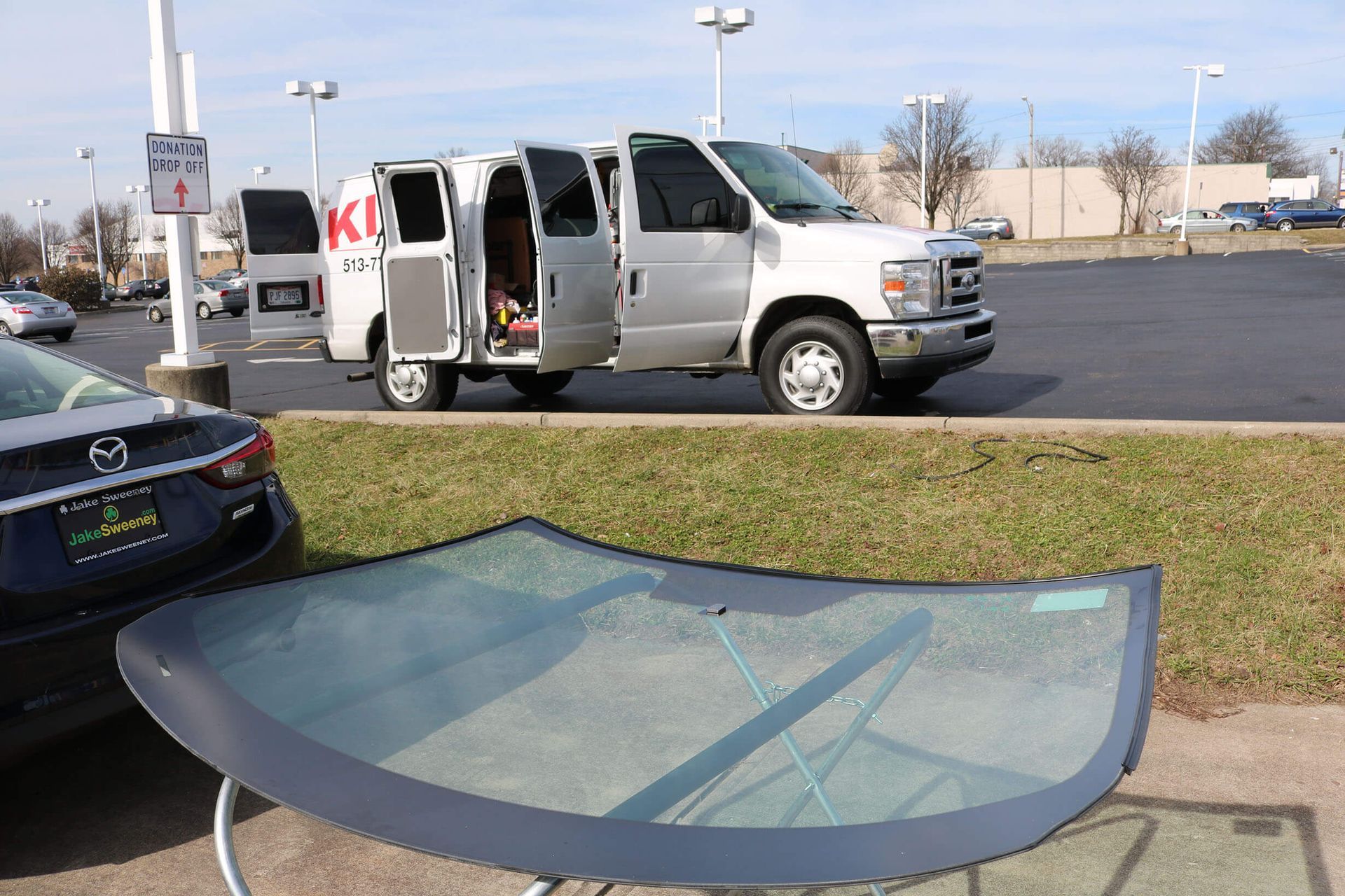 A mazda car is parked next to a van with the door open