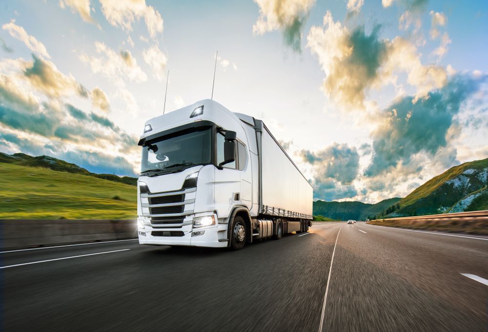 A white semi truck is driving down a highway.