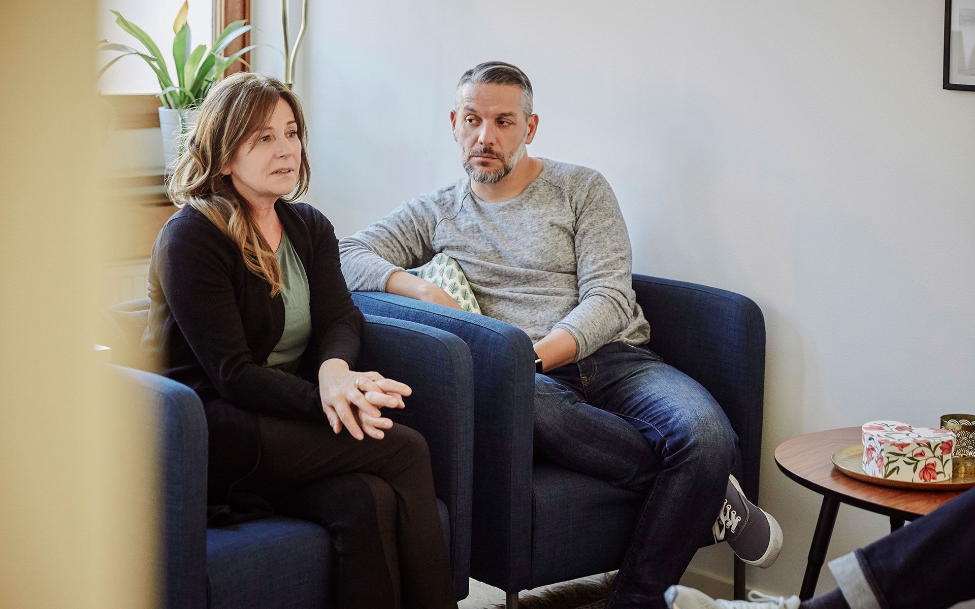 A man and a woman are sitting in chairs in a waiting room.
