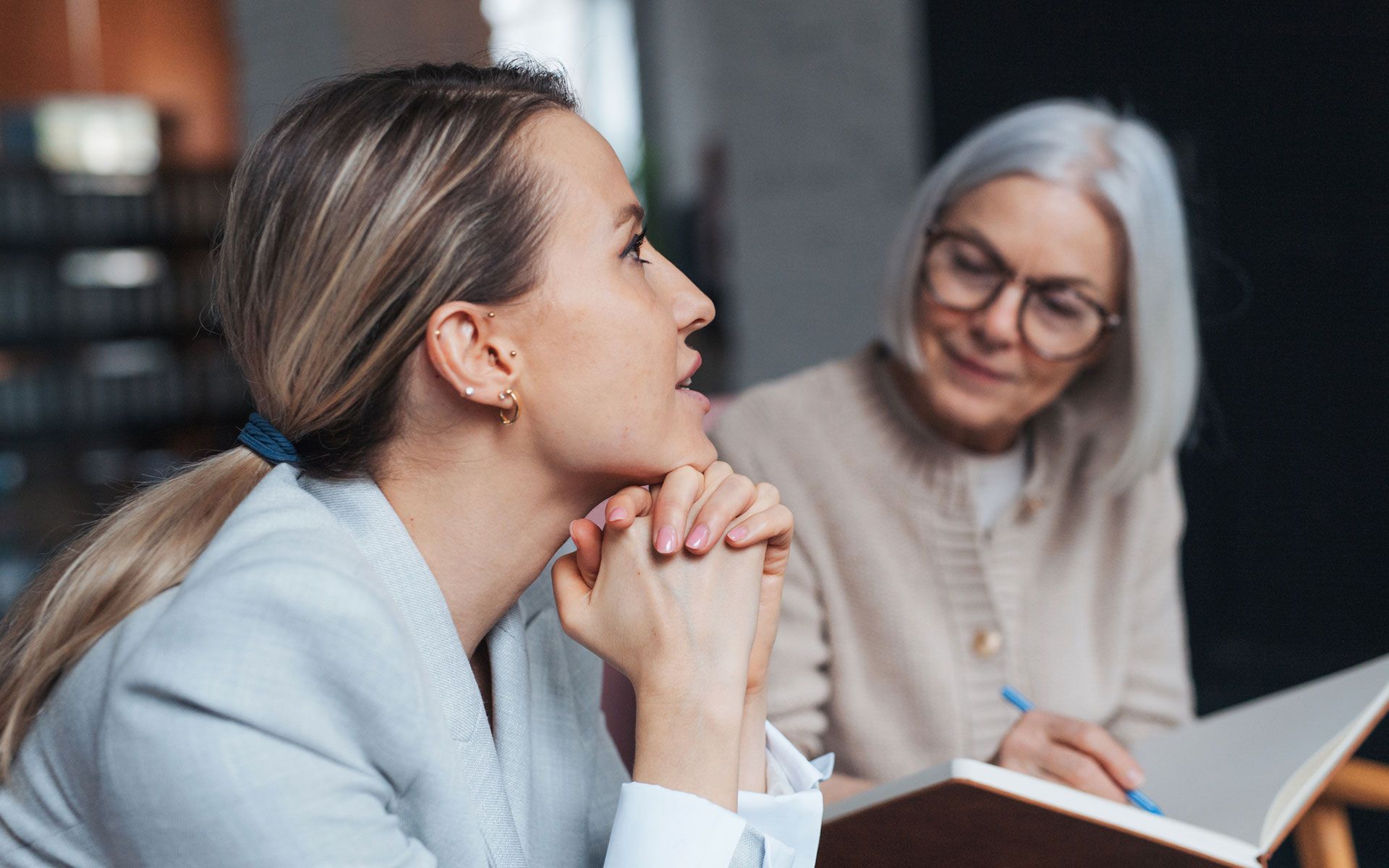 Two women are sitting at a table talking to each other.