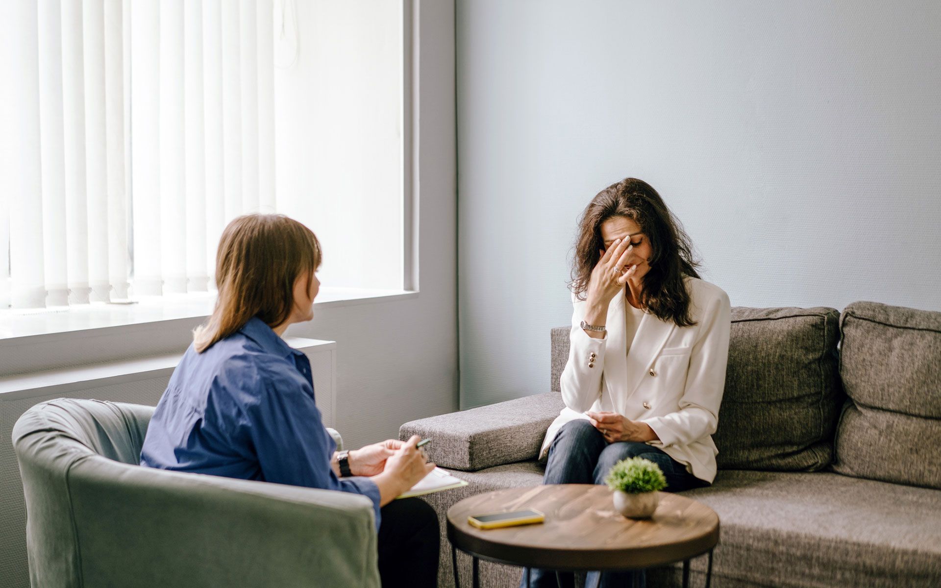 A woman is sitting on a couch talking to a man.