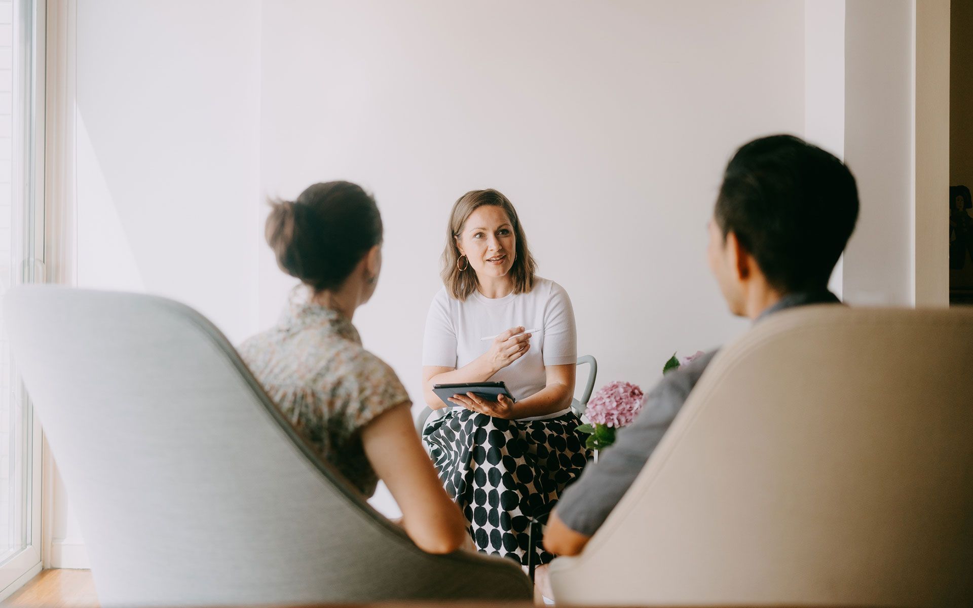 A woman is talking to a man and a woman while sitting in chairs.