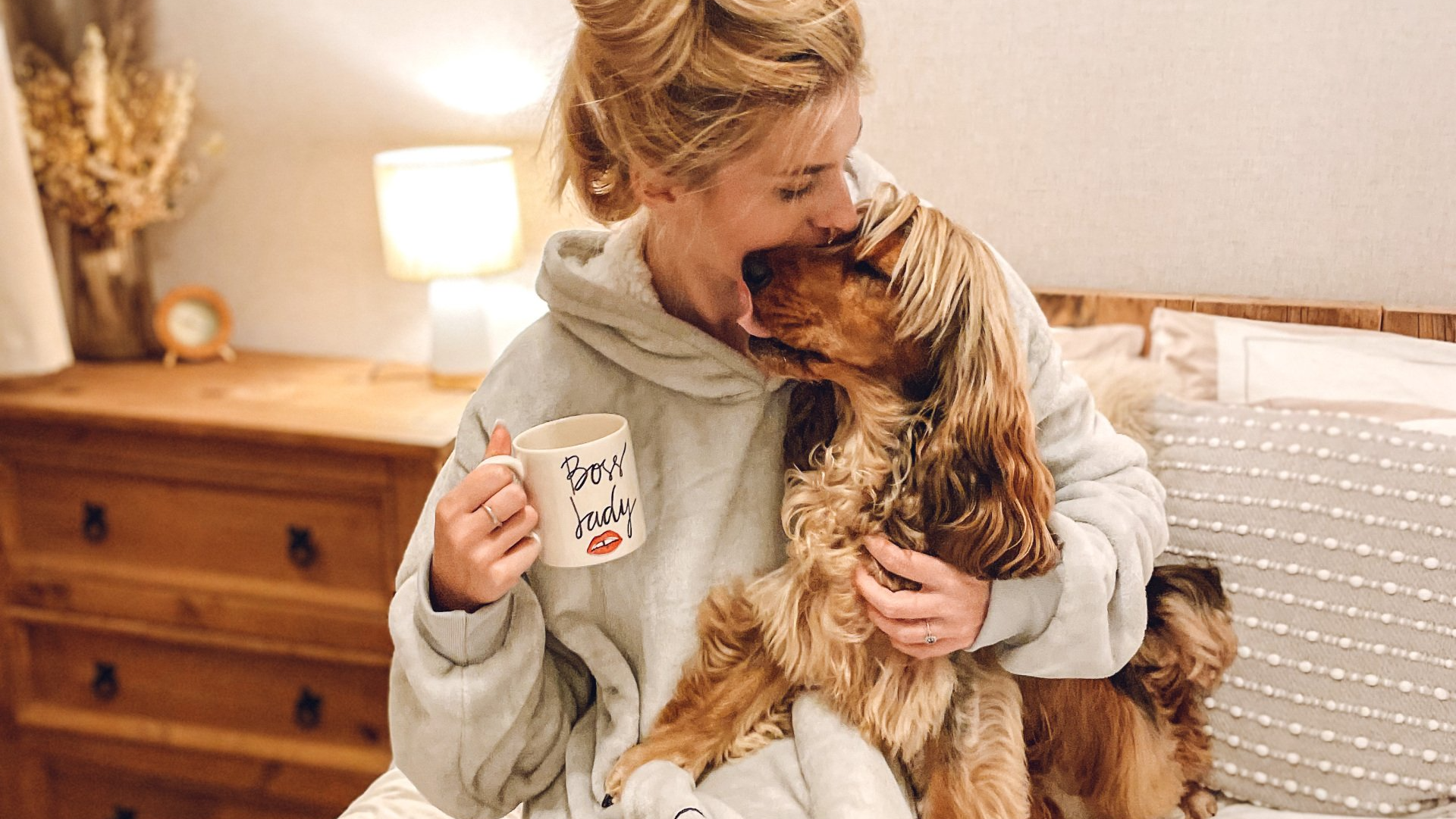 Cocker Spaniel cuddling owner who has mug saying boss lady in her hand and is wearing a Twiggy Tags Snugglywoof giant hoodie