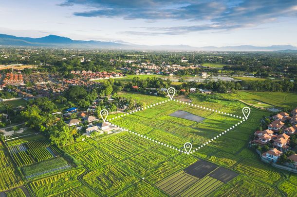 An aerial view of a lush green field with a city in the background.