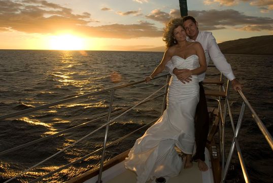 A man and a woman are posing for a picture on a boat in the ocean.